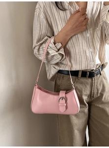 Close-up of a light pink leather baguette bag with a decorative silver metal buckle