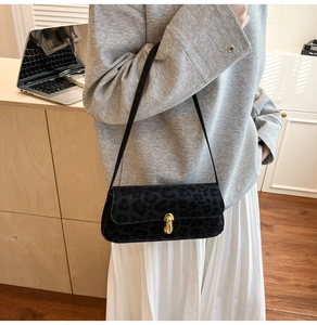 Détail du sac léopard avec fermeture à bouton rotatif en métal doré sur texture velours