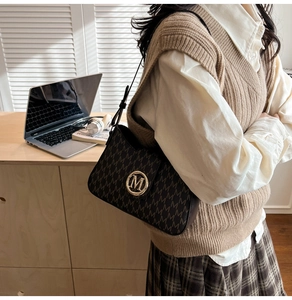 Detail of a brown monogram shoulder bag with gold logo on an aesthetic office desk