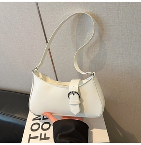 Detail of white leather underarm bag with silver metallic buckle and sleek strap