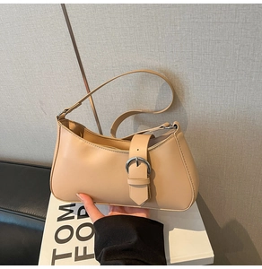 Detailed close-up of light beige underarm bag showing smooth texture and silver buckle