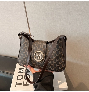 Detail of dark brown leather shoulder bag with logo pattern and golden metal buckle