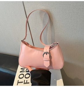 Detail view of pink leather underarm bag featuring decorative strap with silver round buckle