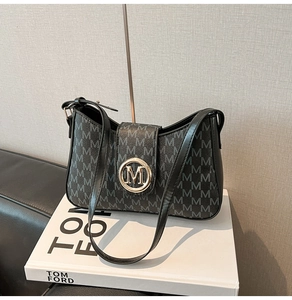 Detailed view of the gold M logo buckle on the black letter-printed underarm bag