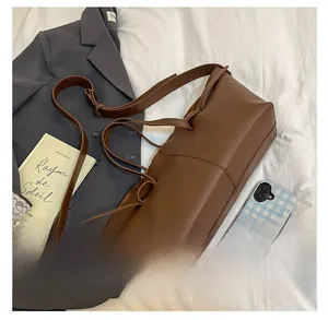 Detailed view of dark brown leather tote bag with vertical stitching and shoulder straps