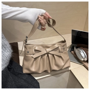 Detail of cream pleated tote bag with bow knot and star rivets in lifestyle setting
