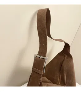Detail of adjustable shoulder strap and silver buckle on vintage brown suede pillow bag