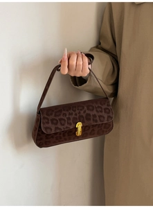 Détail du sac baguette en daim léopard avec fermoir rotatif doré et style rétro élégant