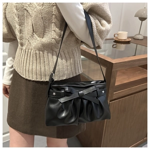 Close-up of a black bow tote bag with silver star accents and cloud pleat texture