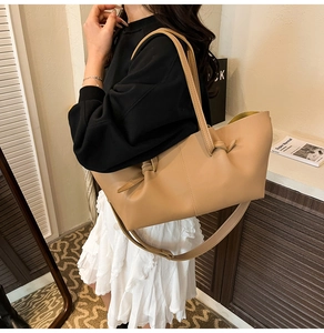 Detail of minimalist beige tote bag with unique leather knot design and wide strap