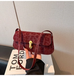 Détail d'un sac baguette léopard rouge avec un fermoir métallique ovale doré chic