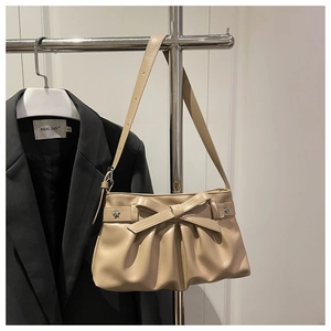 Detail of cream pleated tote bag featuring a leather bow and silver star ornament