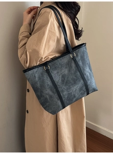 Dettaglio della borsa tote grigia vintage opaca con sottile tracolla in pelle nera e fibbie