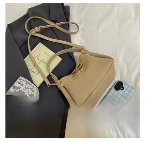 Beige pebble leather bucket bag shown next to a phone for size comparison