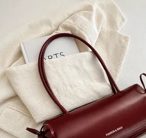 Gros plan du sac porté épaule bordeaux en cuir avec poignée fine et détails chic