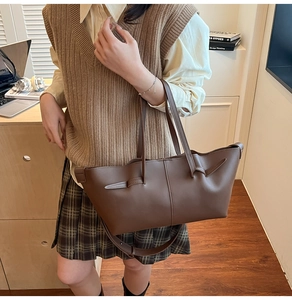 Brown pleated tote bag with adjustable strap shown in a vintage desk setting