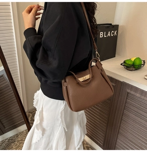 Détail d'un sac cabas en cuir grainé marron foncé avec un fermoir doré tournant chic