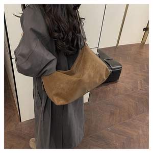 Brown vintage suede hobo bag shown on shoulder over a stylish grey trench coat