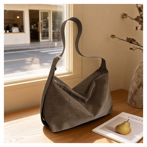 Close-up of retro brown suede shoulder bag with adjustable silver buckle on wood table
