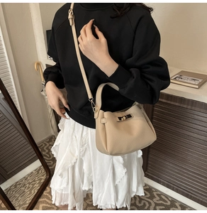 Beige lychee pattern leather bucket bag shown on a model in a cozy interior setting