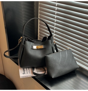 Détail du sac seau noir en cuir grainé avec fermoir doré et pochette assortie