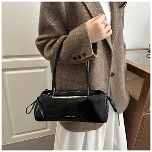 Détail du sac sous le bras noir brillant avec nœuds à cordon et logo argenté imprimé