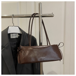 Dettaglio borsa baguette in pelle verniciata marrone scuro con fiocchi su appendino