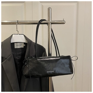 Borsa baguette nera lucida con coulisse appesa a una gruccia con abiti da ufficio