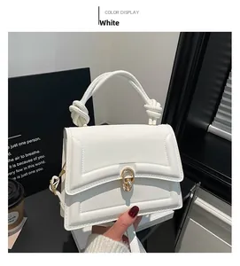 Detailed shot of white leather square handbag featuring knotted handle and gold metal lock