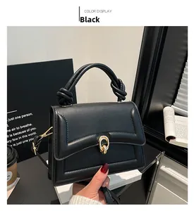 Detail of black quilted leather handbag featuring a unique knotted handle and U-shaped clasp
