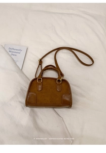 Dettaglio borsa a tracolla in pelle e camoscio marrone con hardware dorato e manico