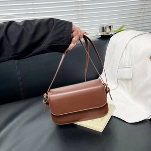 Sac à bandoulière marron minimaliste vintage avec boucles dorées dans un décor de bureau