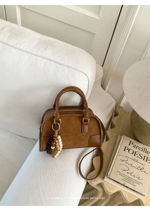 Borsa vintage in ecopelle marrone con nappina di perline su divano in tessuto bianco