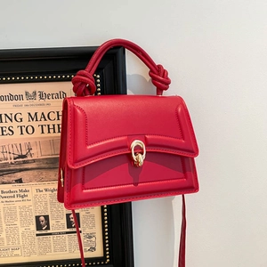 Minimalist red leather handbag with twisted handles and golden ring buckle closure