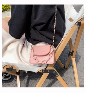 Pink mini crossbody bag featuring a thick chain detail and gold shoulder strap outdoors