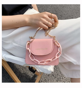 Close-up of a pink mini crossbody bag with gold chain strap and chunky plastic handle