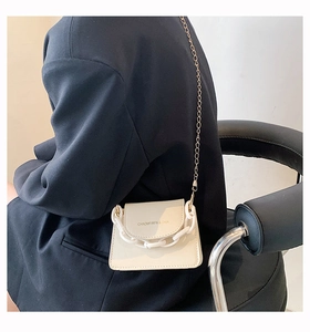 Close-up of off-white mini crossbody bag with gold chain and resin handle on model