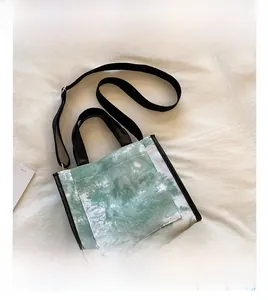 Detail view of green tie-dye canvas tote bag with adjustable black shoulder strap