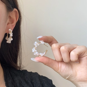 Elegant C-shaped gold hoop earrings with white pearls and sparkling crystals on model