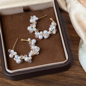 Elegant C-shaped earrings with white pearls and crystals on silk velvet display
