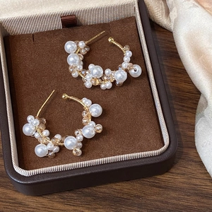 Detail of C-shaped gold pearl earrings with champagne crystals in a jewelry box