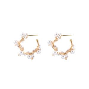 Detail of gold earrings with woven white pearls and champagne crystal beads