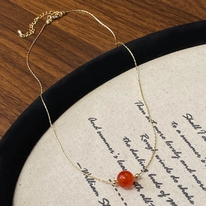 Collier minimaliste chaîne serpent dorée avec une perle d'agate rouge translucide et fermoir