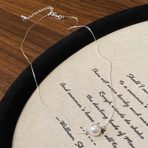 Gros plan d'un collier chaîne serpent en argent avec un pendentif perle ronde blanche
