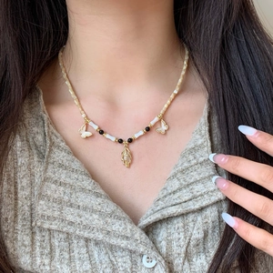 Elegant beaded necklace with gold butterfly pendants and white inserts on female model