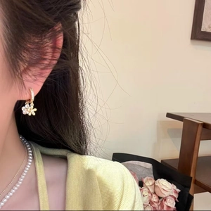Elegant gold flower earrings with white crystals and pearls on model for stylish look