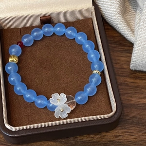 Close-up of light blue beaded bracelet with white floral charms in a jewelry box