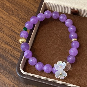 Détail d'un bracelet en perles violettes avec accents dorés et pendentifs floraux