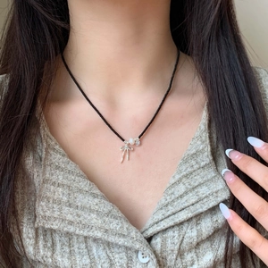 Elegant beaded necklace with silver bow pendant, pearl and black spinel beads on model