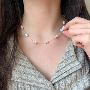 Collier élégant en perles d'eau douce naturelles et chaîne plaquée or porté par un modèle
